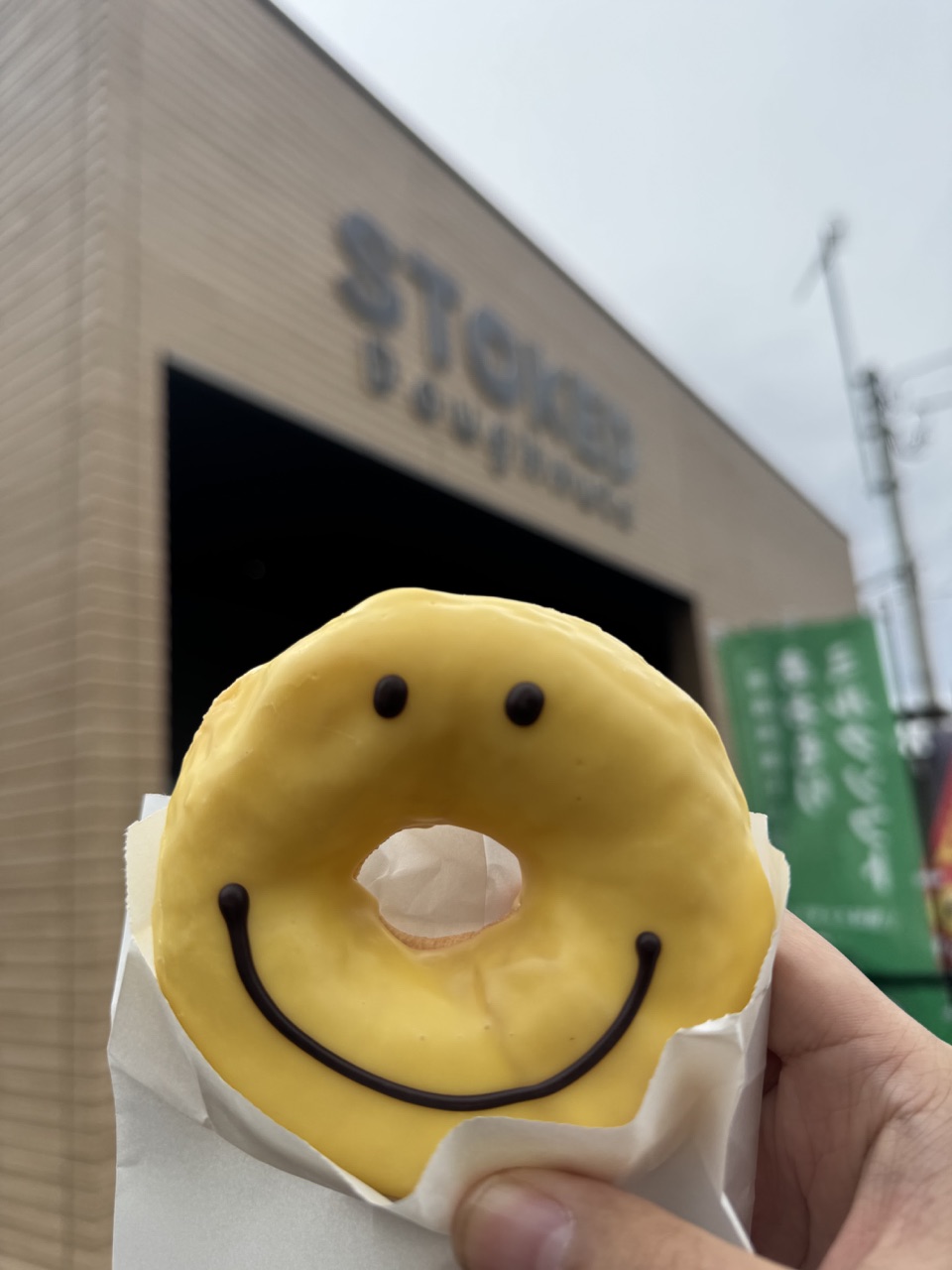 A yellow smiley doughnut held outside a shop during Cooper’s trip to Japan